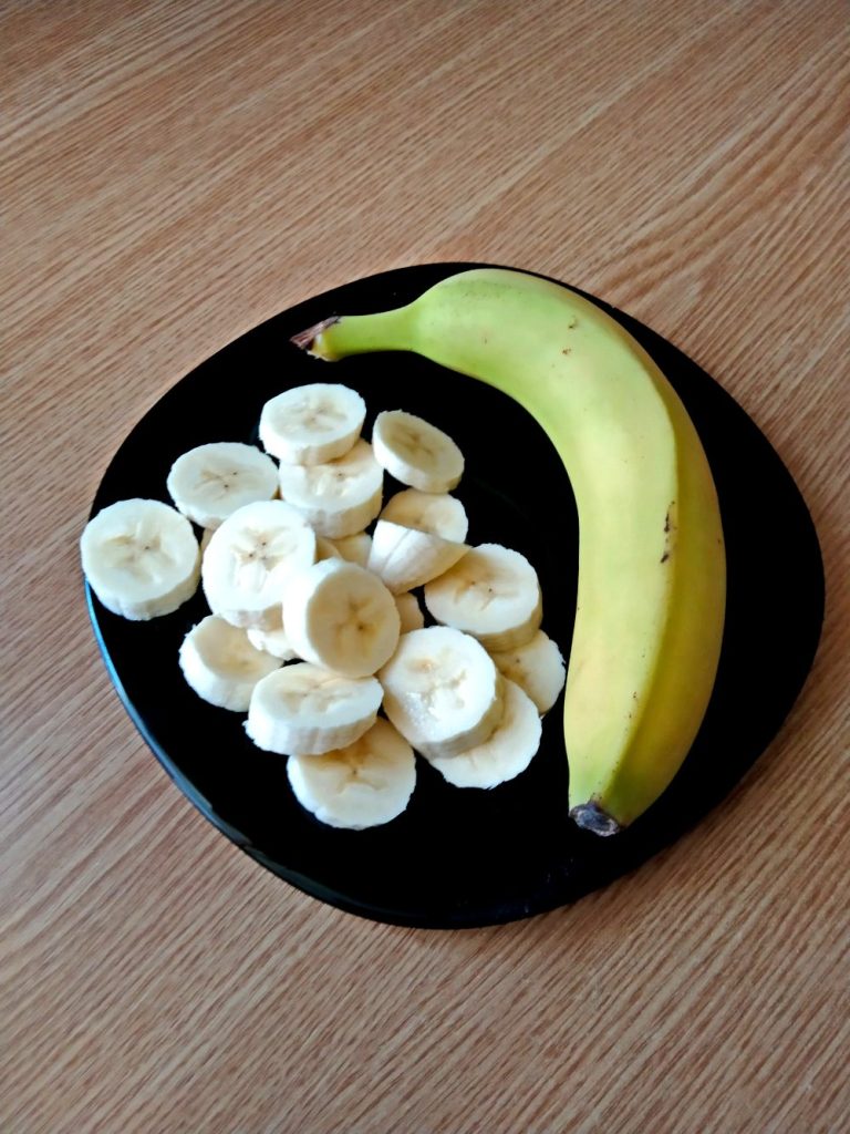 cut and entire banana on black plate on a table