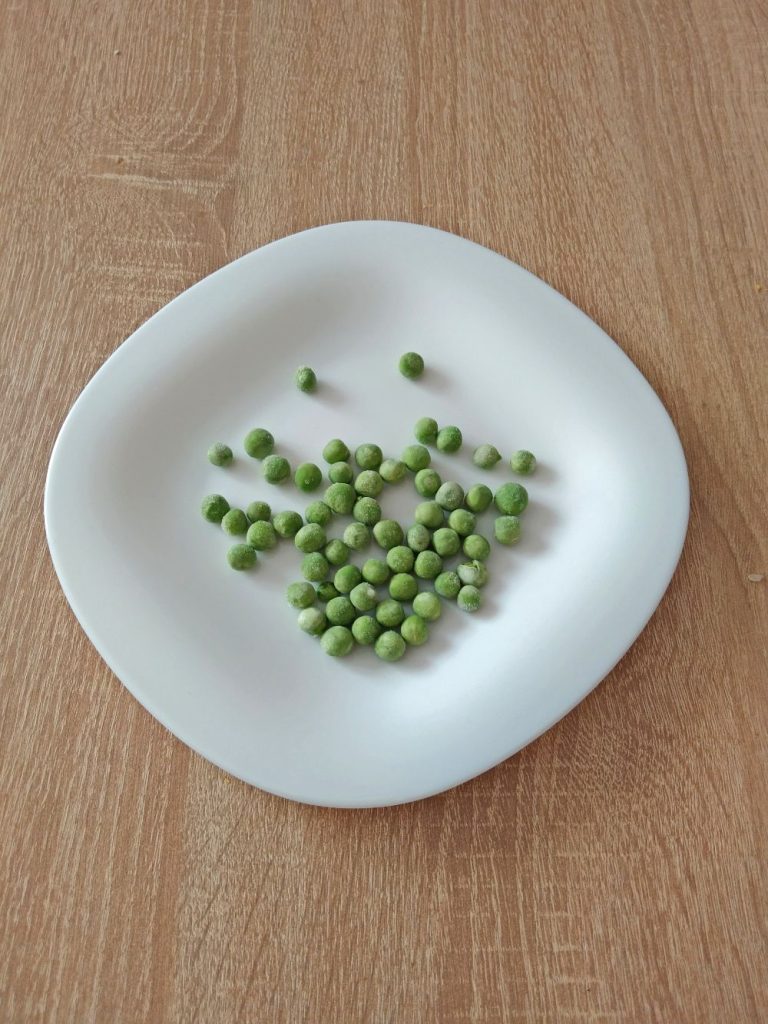 Green peas on a white plate on the table